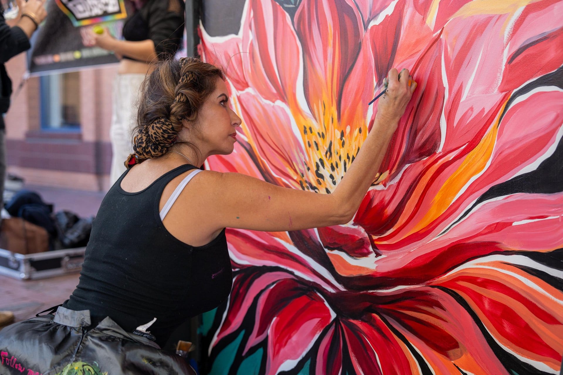 Artist painting a vibrant flower mural in Downtown Tempe.
