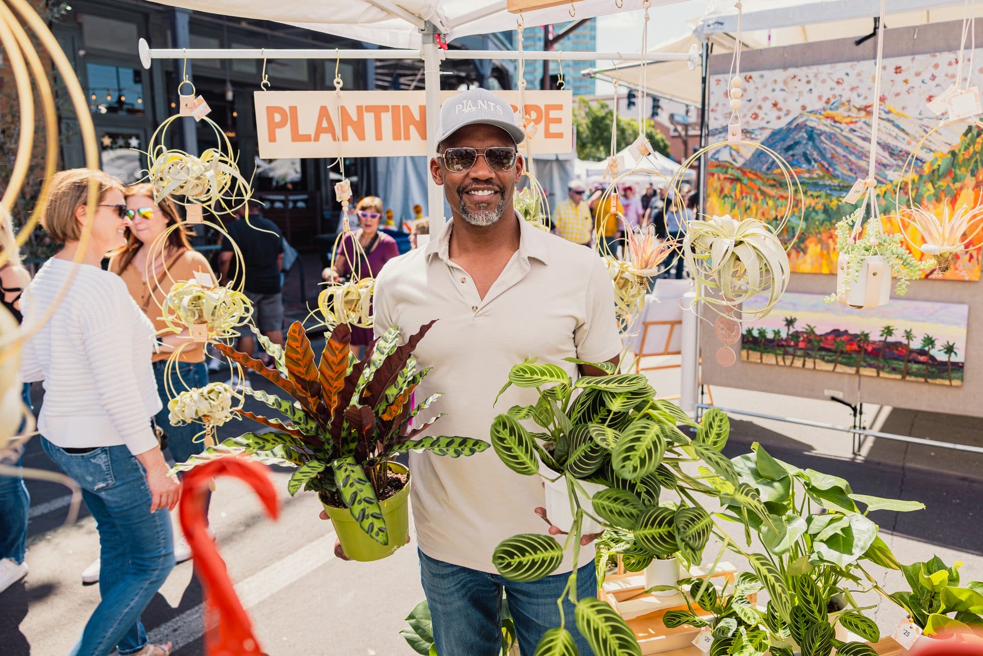Plant vendor selling greenery at Tempe Festival of the Arts with visitors walking by