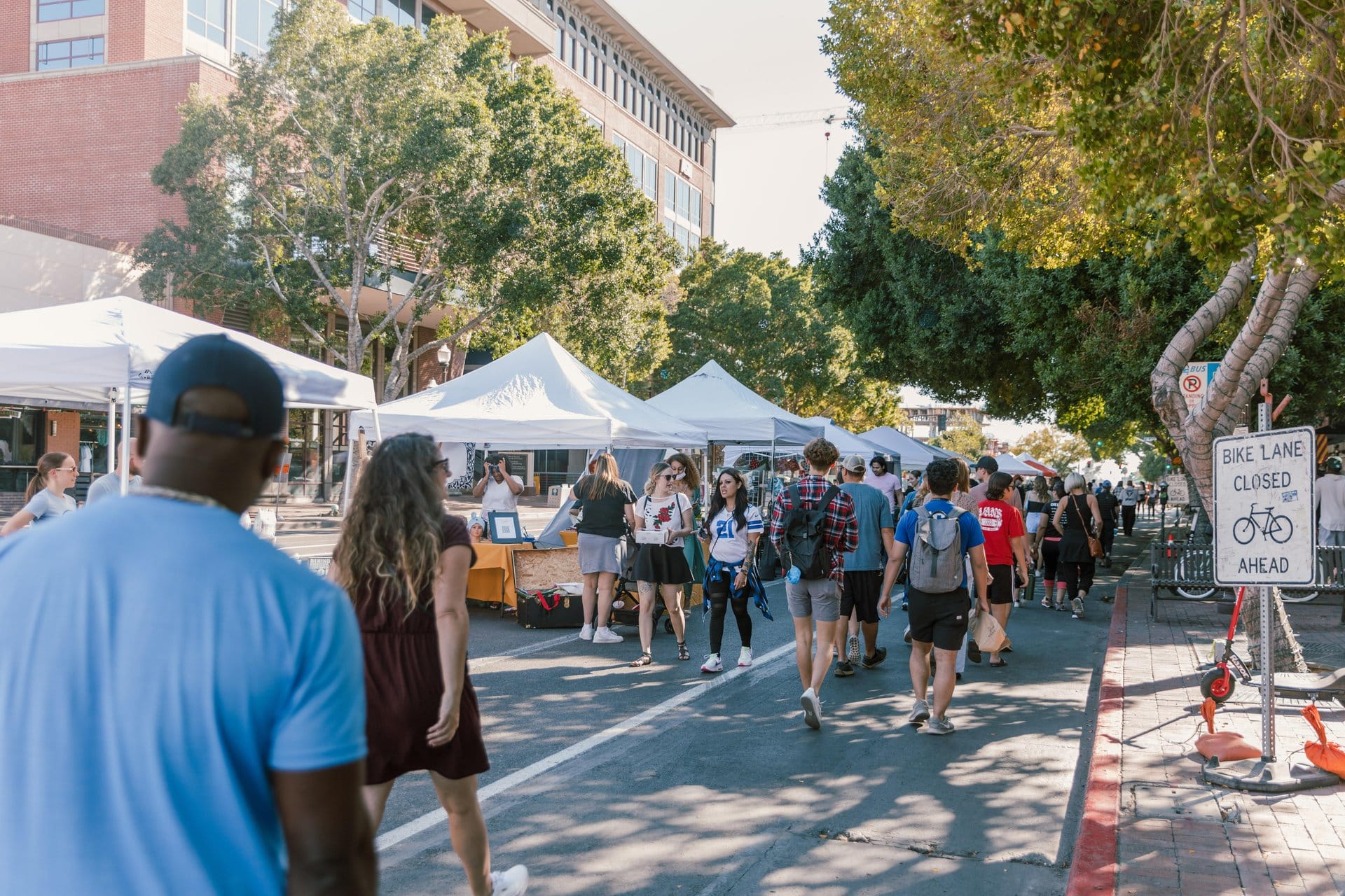 Shoppers browsing booths at an outdoor market during 2nd Sundays on Mill in Tempe, Arizona