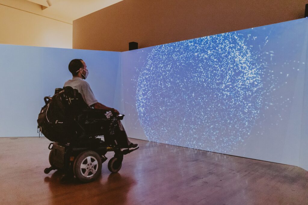 A man in a wheelchair looking at an art projector screen inside the ASU Art Museum