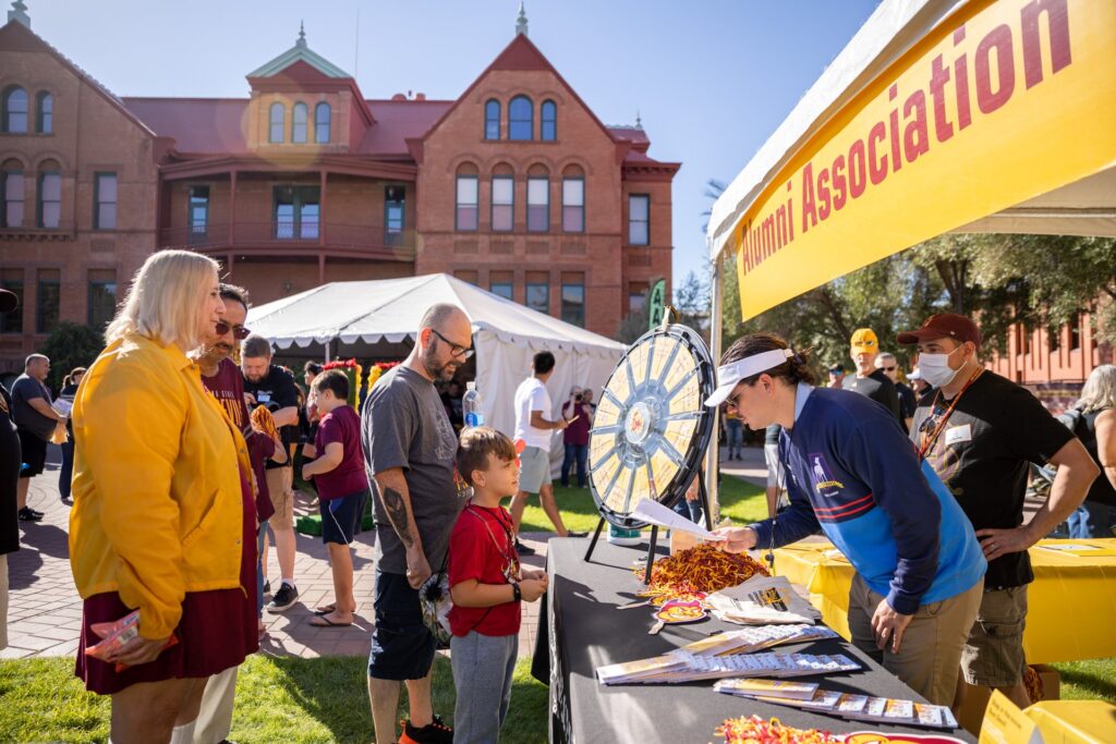 A man and child is lined up to play "Spin the Wheel" game at a booth