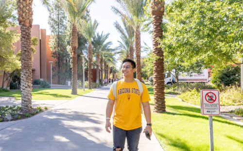 A male ASU Student walking down Palm Walk