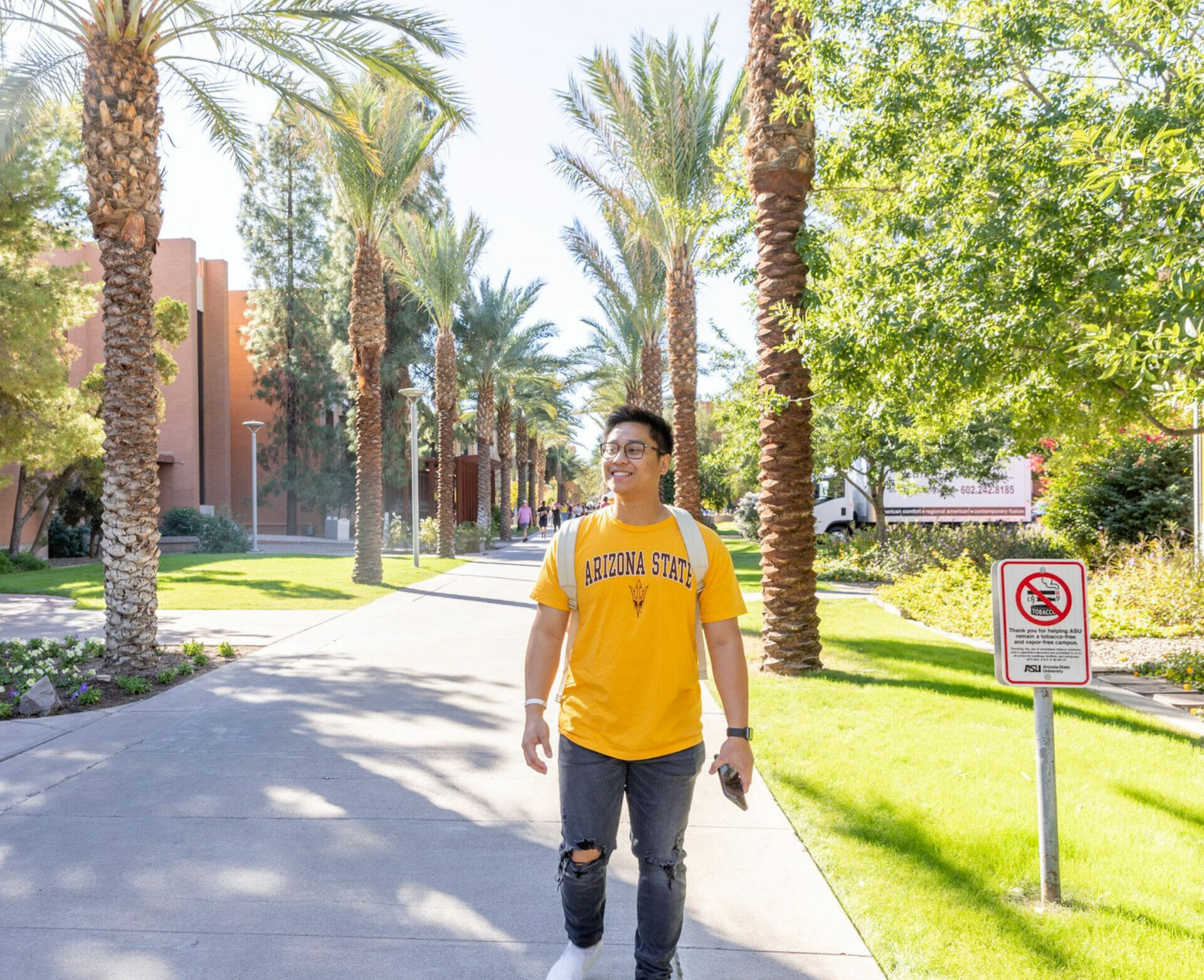A male ASU Student walking down Palm Walk