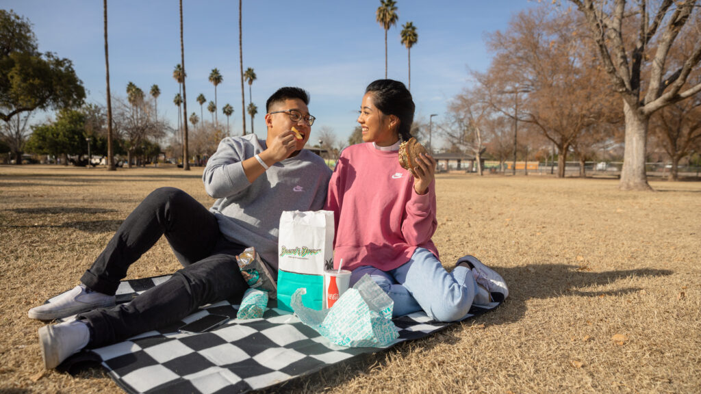 A smiling couple enjoys a picnic in the park.
