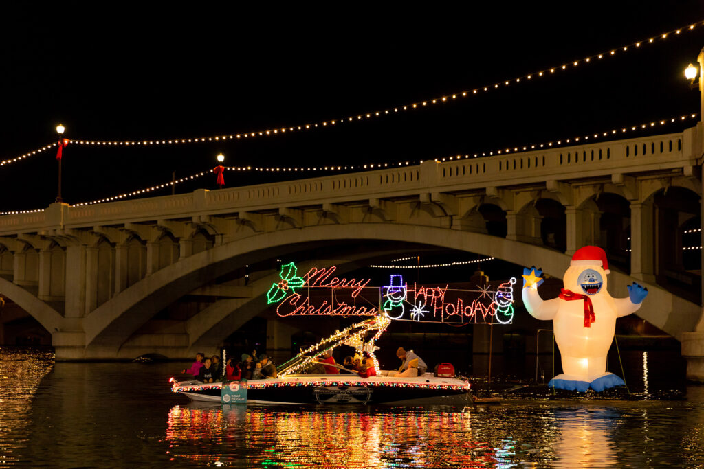 Holiday-Decorated boat at Tempe Town Lake with a lit sign that says "Merry Christmas Happy Holidays"