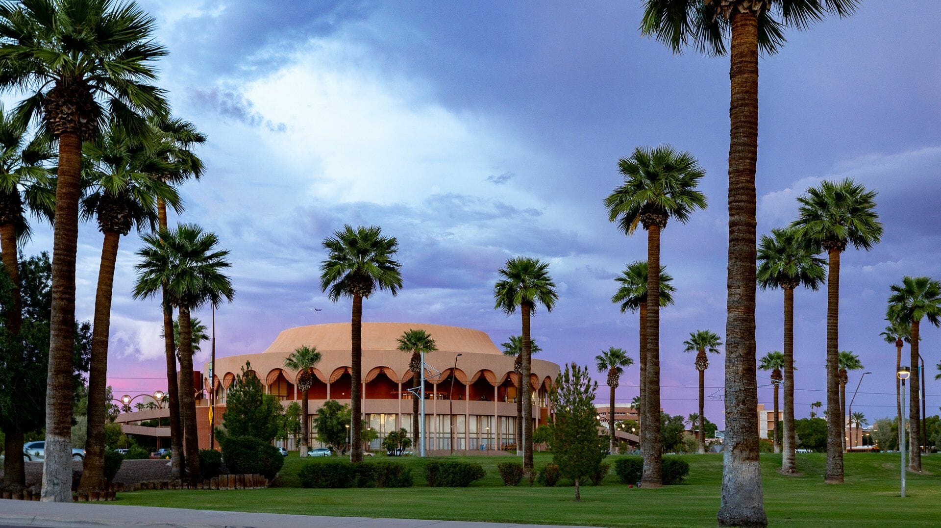 ASU Gammage with palm trees in the front and with a purple hue sunset in the background and