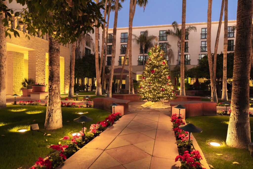 A lit up Christmas tree in the middle of a hotel courtyard