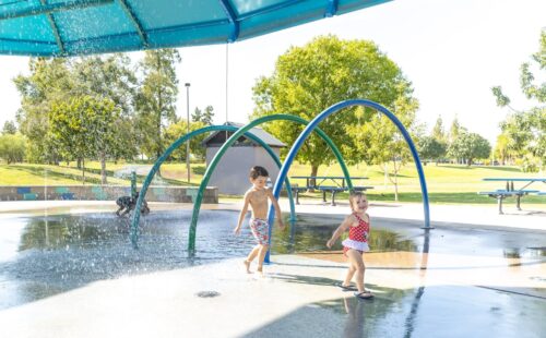 two kids running through a splash pad