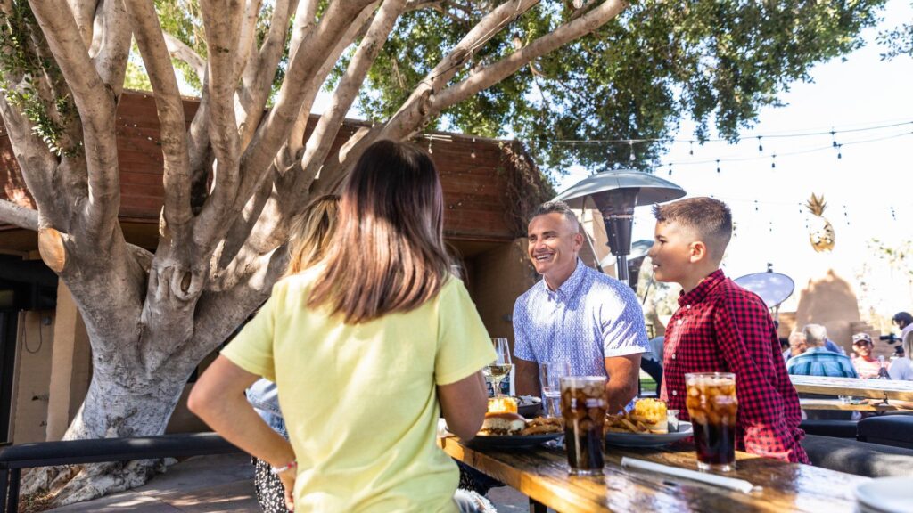 Patio of The Golden Pineapple with a family smiling and eating