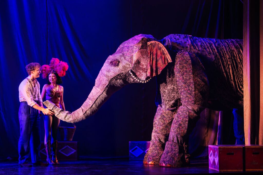 Two actors on stage with an elephant during performance
