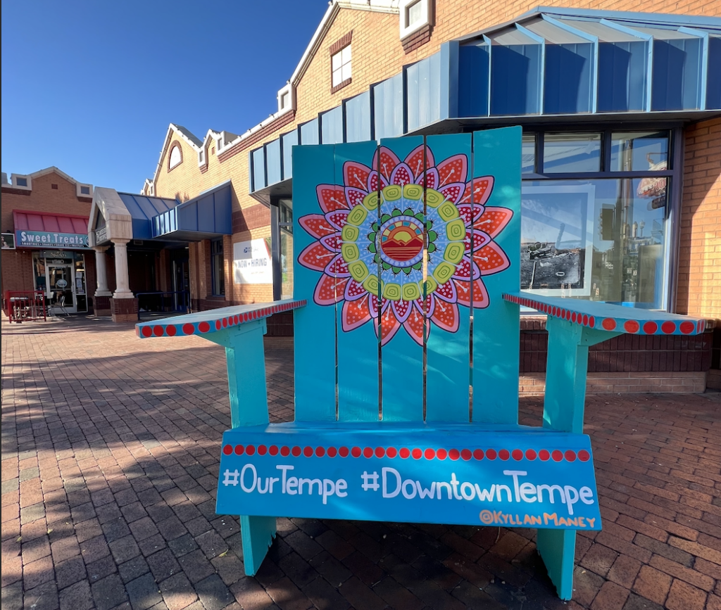 A giant, colorfully painted beach chair sits on the sidewalk of Downtown Tempe.